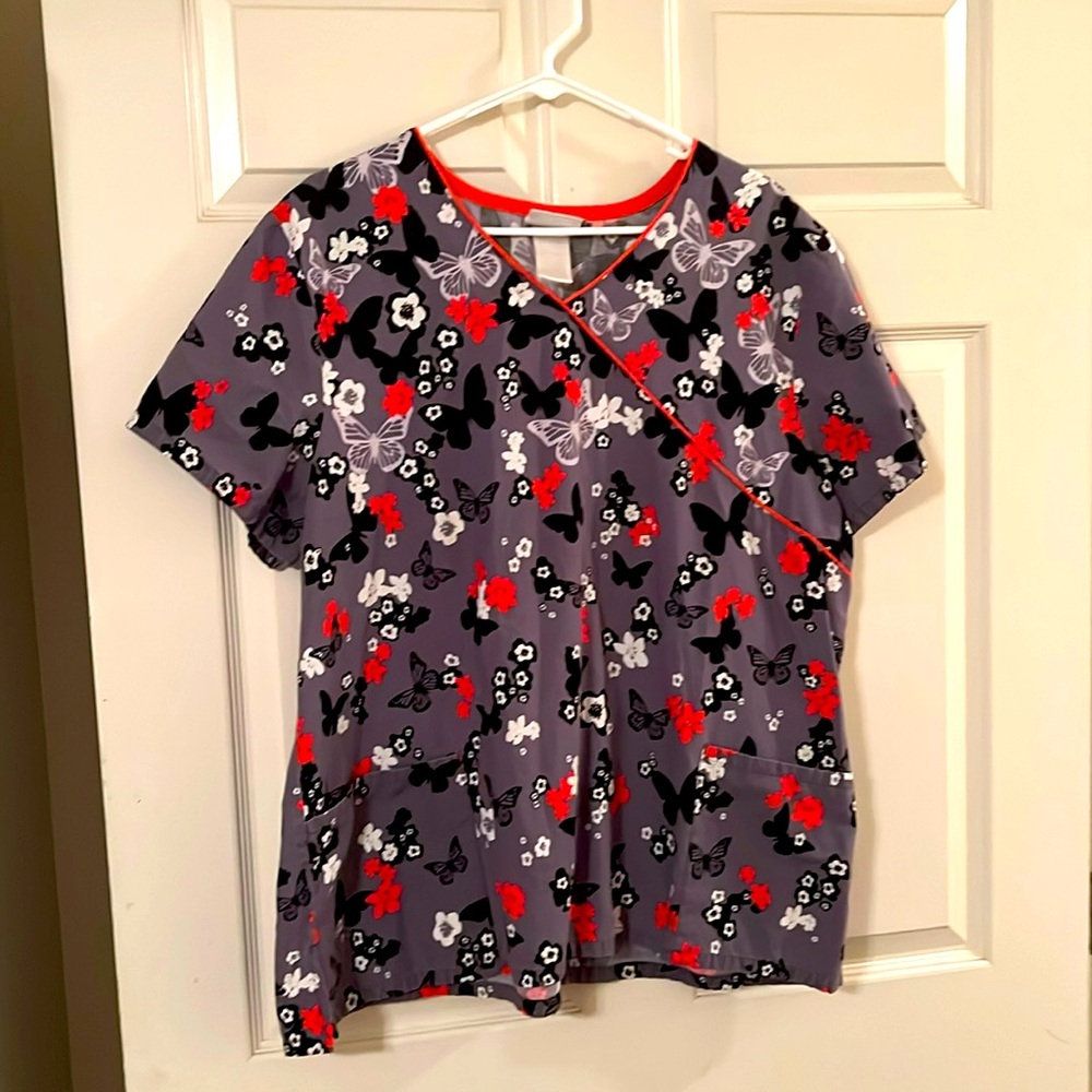 V-neck ladies scrub. Faded tag says 2X size with butterfly and flower pattern.